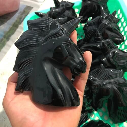 A natural obsidian sculpture of a horseshoe unicorn with a quartz crystal skull