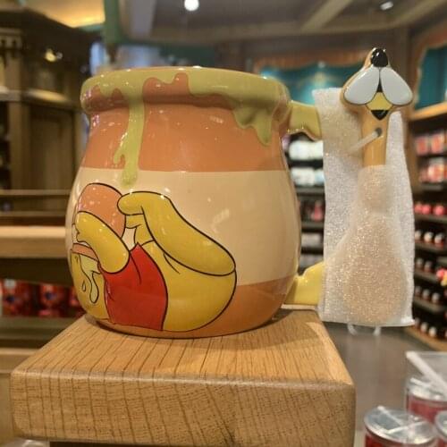 Winnie the Pooh drinks from a honey-lided mug and a glass of water from a ceramic mug at Disneyland
