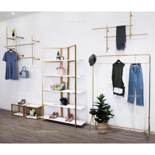 Clothing store display stand. Wall-hung in The Wall. Womens clothing store simple wrought iron gold. Side hangers