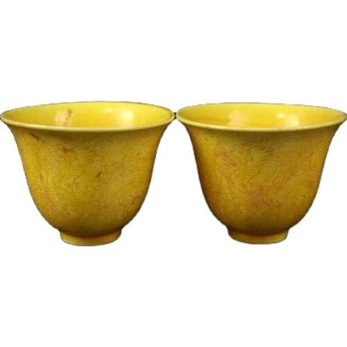 A pair of yellow glaze carved dragon pattern cups from Chinas early collection
