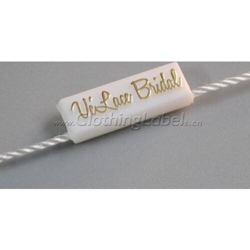 Hang tag string, plastic seal, white background with gold logo, attach to hang tag, clothing label accessories