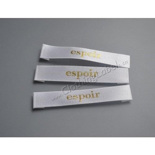 Custom fabric woven clothing labels, white background, gold logo, with size label. Price doesn't include size label
