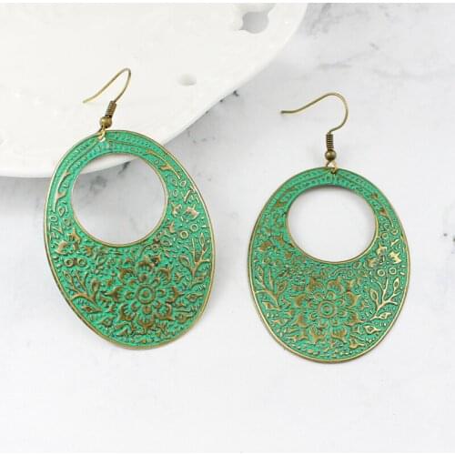 The cyan ellipse has a hollow rounded circle inside and is surrounded by large flowers and vines to form a vintage earring