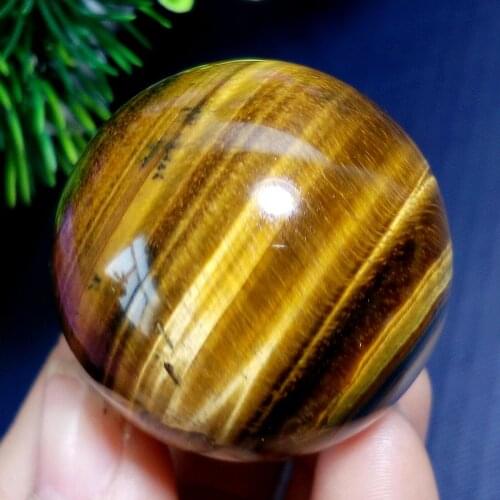 A natural red tiger eye stone sphere surrounding a crystal ball heals the tiger eye