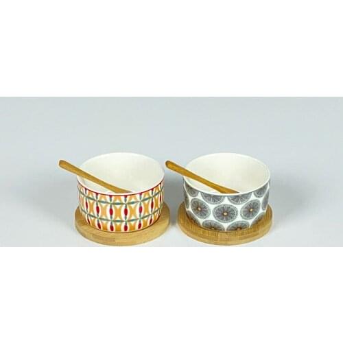 Different colored porcelain sause bowl set within two pieces two bamboo spoons on bamboo base