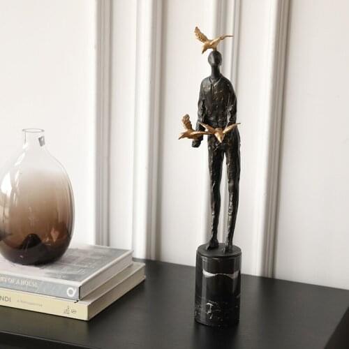 MODERN ABSTRACT CHARACTER STAND ON BLACK CYLINDRICAL MARBLE STROKING GOLDEN BIRD SCULPTURE CREATIVE METAL STATUE FOR HOME DECOR