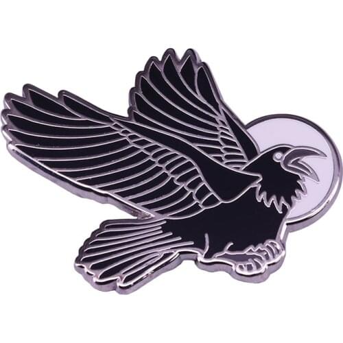 This Raven Crow Goth Witch Enamel Pin Depicts a black birds flight across the paths of the moon